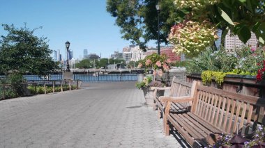 New York City rıhtımı, Manhattan silueti Downtown Rockefeller Park 'tan Hudson Yards nehir manzaralı gökdelenler. Deniz kenarı manzarası, Birleşik Devletler mimarisi. Yaz çiçekleri rüzgarda, bankta açar..