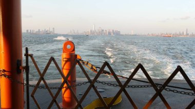 New York City feribottan Staten Island 'a ufuk çizgisi. Manhattan şehir merkezinde. Feribottan Dünya Ticaret Merkezi gökdelenine. Nehir kıyısı günbatımı manzarası, nehir kenarındaki binalar, Fidi, ABD