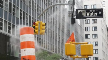 New York Su Sokağı 'nda buhar sızıntısı, turuncu buhar borusu yığını. Pipo dumanı. Con Edisons Buhar Operasyonları Sistemi, Manhattan şehir merkezi finans bölgesi mimarisi. Trafik ışığı