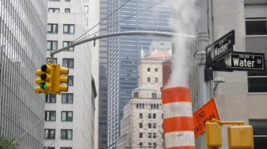 New York Su Sokağı 'nda buhar sızıntısı, turuncu buhar borusu yığını. Pipo dumanı. Con Edisons Buhar Operasyonları Sistemi, Manhattan şehir merkezi finans bölgesi mimarisi. Trafik ışığı