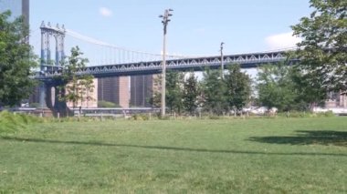 Manhattan Köprüsü 'nden Brooklyn Dumbo' ya. New York 'un sembolü, Amerika' nın seyahat yeri. Birleşik Devletler 'in mimarisi, turizm simgesi. Kablolu yayın köprüsü. Park yeşili, nehir kenarında yeşil çimen pikniği..