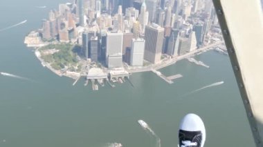 New York City 'nin kapıları helikopter uçuşuna kapalı. Helikopter Manhattan' ın üzerinde uçuyor. Dünya Ticaret Merkezi. Ayaklar spor ayakkabılarda, turist bacakları, ayakkabılar selfie pov. Amerika 'ya uçuk seyahat. Kamera sallanıyor..