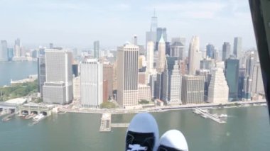 New York City 'nin kapıları helikopter uçuşuna kapalı. Helikopter Manhattan' ın üzerinde uçuyor. Dünya Ticaret Merkezi. Ayaklar spor ayakkabılarda, turist bacakları, ayakkabılar selfie pov. Amerika 'ya uçuk seyahat. Kamera sallanıyor..