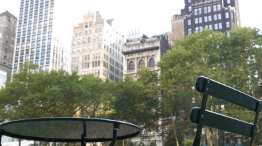 New York City, Manhattan Midtown Bryant Park with Public library, 42 street and 5th Fifth 5 avenue corner, United States. NYC landmark in USA. Empty chair and table in summer greenery. clipart