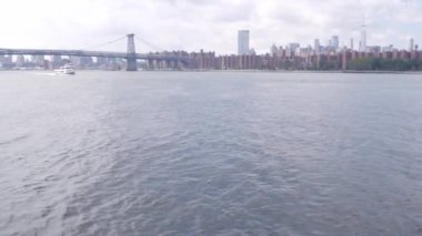Feribottan New York City silueti. Manhattan şehir merkezindeki gökdelenler feribottan görünüyor. Doğu nehri kıyısı manzarası, nehir kıyısındaki binalar ABD suları yakınında. Williamsburg Köprüsü