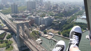 New York Şehri 'nin kapıları kapalı, helikopter Manhattan Brooklyn Köprüsü üzerinde uçuyor, Birleşik Devletler. Ayaklar ayakkabıda, bacaklar ayakkabıda, selfie pov. Ekstrem turist macerası, Amerika seyahati. Kamera sallanıyor..