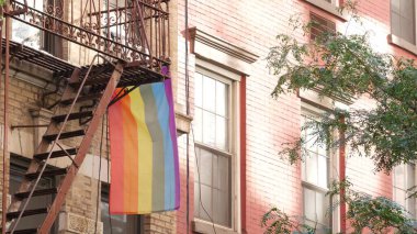 New York City mimarisi, Manhattan USA. Şehir dışındaki konutlar. LGBT gökkuşağı bayrağı, Birleşik Devletler. Tipik kırmızı tuğla cephesi. Yangın merdiveni. Homoseksüel sembolü. Gurur