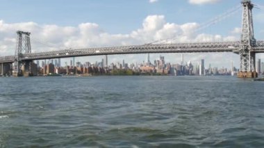 Feribottan New York City silueti. Manhattan şehir merkezindeki gökdelenler feribottan görünüyor. Doğu nehri kıyısı manzarası, nehir kıyısındaki binalar ABD suları yakınında. Williamsburg Köprüsü