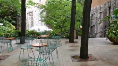 New York şehri hayatı, şehir parkı, Greenacre Park şelalesi. Amerikan Manhattan Midtown, ABD. Eğlence bölgesi yaz çiçekleri, ağaçlar yeşillik. Boş sandalyeler ve masalar. New York 'ta yeşil vaha.