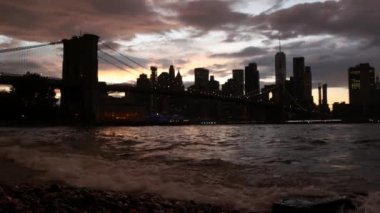 Brooklyn Köprüsü, New York City Manhattan şehir merkezi silueti, finans bölgesi şehir manzarası. Birleşik Devletler Dünya Ticaret Merkezi gökdeleni. Waterfront Pebble Sahili, Dumbo, ABD. Dramatik alacakaranlık bulutlu gökyüzü.