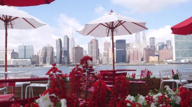 New York şehri kıyısı silueti, Manhattan şehir merkezi binaları, nehir kıyısındaki gökdelenler, doğu nehri kıyısındaki kafe şemsiyeleri. Hunters Point, Long Island, Queens, ABD 'den liman kenti manzarası.