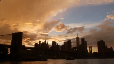 Brooklyn Köprüsü ve New York City Manhattan şehir merkezi silueti, finans bölgesi şehir manzarası. Birleşik Devletler Dünya Ticaret Merkezi gökdeleni. Waterfront Pebble Sahili, Dumbo, ABD. Dramatik gün batımı bulutlu gökyüzü