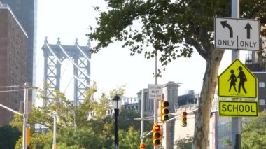 Okul bölgesi sarı yol işareti, insanlar karşıya geçiyor. Manhattan şehir merkezinde, New York City mimarisinde çocuk güvenliği. Eğitim sembolü ABD. İleride yayalar, trafik işaretleri ve Manhattan Köprüsü