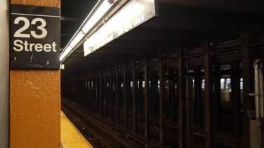 New York metro istasyonu içi, yeraltı metro platformu tabelası. Metro treni, demiryolu yolcusu toplu taşıma, Birleşik Devletler. Yazı tahtası: 23. Cadde. Midtown, Manhattan, New York.