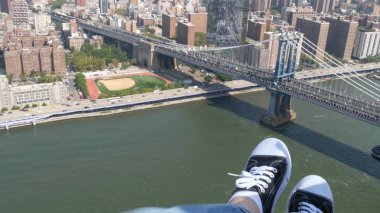 New York Şehri 'nin kapıları kapalı, helikopter Manhattan Brooklyn Köprüsü üzerinde uçuyor, Birleşik Devletler. Ayaklar ayakkabıda, bacaklar ayakkabıda, selfie pov. Ekstrem turist macerası, Amerika seyahati. Kamera sallanıyor..