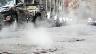 Rögar kapağından sıcak duman, Con Edisons Buhar Sistemi New York, ABD 'de. Beaver Caddesi 'ndeki yol buharı, NYC Finansal Bölge, Aşağı Manhattan, ABD. Şehir manzarası, alçak açı. Arabalar