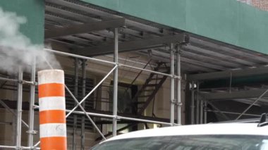 New York caddesinde buhar sızıntısı, turuncu buhar borusu yığını. Pipo dumanı. Con Edisons Buhar Operasyonları Sistemi, 5. Cadde, Manhattan Midtown. ABD 'de yapı iskelesi..
