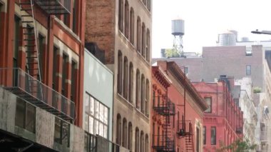 New York City Manhattan mimarisi. Şehir dışındaki konutlar. ABD 'de gayrimenkul. Kırmızı tuğla cephe. Yangın çıkışı, acil merdiven çıkışı. Çatıdaki su kulesi, çatıdaki tank..