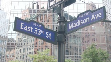 New York City kavşağı, Manhattan köşesi, Madison Bulvarı, sokak kavşağı tabelası. Midtown merkez bölgesi mimarisi, Birleşik Devletler. Tek yönlü ok işareti, gökdelenler. Düşük açı.