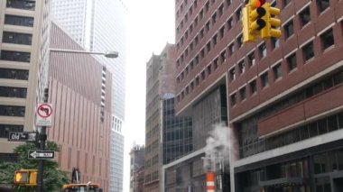 New York Su Sokağı 'nda buhar sızıntısı, turuncu buhar borusu yığını. Pipo dumanı. Con Edisons Buhar Operasyonları Sistemi, Manhattan şehir merkezi finans bölgesi mimarisi. Trafik ışığı