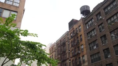 New York City klasik bina mimarisi. Şehir dışındaki konutlar. ABD 'de gayrimenkul. Amerika 'da tipik bir tuğla cephesi. Çatıdaki su kulesi, çatıdaki tank. Yangın merdiveni