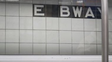 New York metro istasyonu duvarı, yeraltı metro platformu tabelası. Metro treni, yolcu taşımacılığı. E Bway 'den mesaj geldi. Broadway NYC 'de. Manhattan şehir merkezi trafiği. Birleşik Devletler