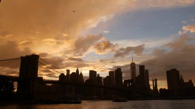 Brooklyn Köprüsü ve New York City Manhattan şehir merkezi silueti, finans bölgesi şehir manzarası. Birleşik Devletler Dünya Ticaret Merkezi gökdeleni. Waterfront Pebble Sahili, Dumbo, ABD. Dramatik gün batımı bulutlu gökyüzü