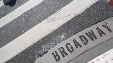 Broadway sokak tabelası, yaya zebra kavşağındaki insanlar. New York City Manhattan kavşağı. Yaya geçidinde asfalt, kavşaktaki gölgeler. Trafik levhası, Birleşik Devletler