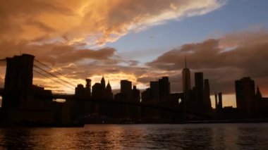 Brooklyn Köprüsü ve New York City Manhattan şehir merkezi silueti, finans bölgesi şehir manzarası. Birleşik Devletler Dünya Ticaret Merkezi gökdeleni. Waterfront Pebble Sahili, Dumbo, ABD. Dramatik gün batımı bulutlu gökyüzü