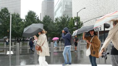 New York, Birleşik Devletler - 10 Eylül 2023: Manhattan Şehir Merkezi Finans Bölgesi. Yağmurlu bir günde şemsiyesi olan insanlar. Dünya Ticaret Merkezi Oculus, anıt havuzları ve 911 Müze alanı, Greenwich Caddesi.