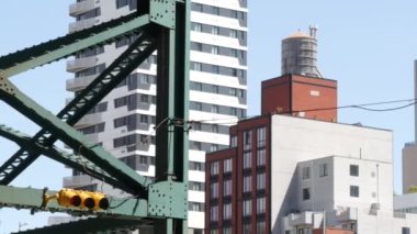New York metrosu, metropol köprüsü, caddenin üstündeki metro yolu. Demiryolu taşımacılığı. Demiryolu hattı. Queens toplu taşımacılığı. Long Island City, Birleşik Devletler. Çatıdaki su kulesi..