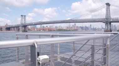 Feribottan New York City silueti. Manhattan şehir merkezindeki gökdelenler feribottan görünüyor. Doğu nehri kıyısı manzarası, nehir kıyısındaki binalar ABD suları yakınında. Williamsburg Köprüsü