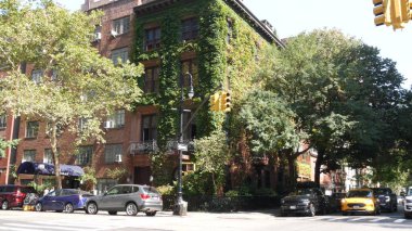 New York City, ABD, 6 Eylül 2023 Manhattan şehir merkezi Irving sokak köşesi, kavşak, Gramercy, ABD. İnsanlar yayalar. Sarı taksi. Sarmaşık yapraklarıyla kaplı kırmızı tuğladan ev