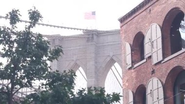 Dumbo 'dan New York City Brooklyn Köprüsü' ne. Kırmızı tuğla duvar, eski tarihi tütün deposu, Market ve Tiyatro. Düşük açı. Sembolik simge altında kemerli pencereler. Amerika Birleşik Devletleri, ABD mimarisi