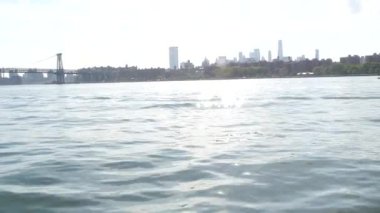 Feribottan New York City silueti. Manhattan şehir merkezindeki gökdelenler feribottan görünüyor. Doğu nehri kıyısı manzarası, nehir kıyısındaki binalar ABD suları yakınında. Williamsburg Köprüsü