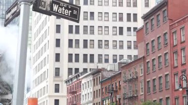 Buhar sızıntısı, New York Su Sokağı, turuncu buhar boruları. Pipo dumanı. Con Edisons Buhar Operasyonları Sistemi, Manhattan şehir merkezi finans bölgesi mimarisi. Kırmızı tuğla ev