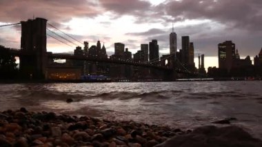 Brooklyn Köprüsü, New York City Manhattan şehir merkezi silueti, finans bölgesi şehir manzarası. Birleşik Devletler Dünya Ticaret Merkezi gökdeleni. Waterfront Pebble Sahili, Dumbo, ABD. Dramatik alacakaranlık bulutlu gökyüzü.