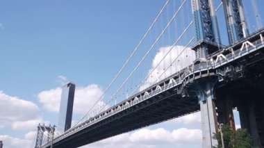 Manhattan Köprüsü 'nden Brooklyn Dumbo' ya. New York 'un sembolü, Amerika' nın seyahat yeri. Birleşik Devletler 'in mimarisi, turizm simgesi. Kablolu yayın köprüsü. Deniz kenarındaki parktan kablolar ve gökyüzü. Düşük açı.