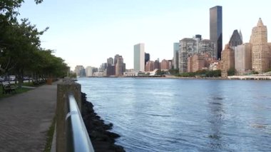 New York şehri kıyısı silueti, Manhattan şehir merkezi binaları, nehir kıyısındaki gökdelenler, doğu nehri suyu. Roosevelt Adası 'ndan deniz kenarı manzarası. Birleşik Devletler mimarisi ve gayrimenkul.