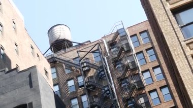 New York City klasik bina mimarisi. Şehir dışındaki konutlar. ABD 'de gayrimenkul. Amerika 'da tipik bir tuğla cephesi. Çatıdaki su kulesi, çatıdaki tank. Yangın merdiveni