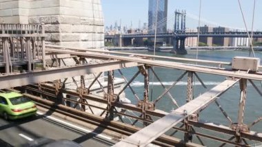 Brooklyn Köprüsü 'nde arabalar, New York Şehri Midtown ve Manhattan Köprüsü manzaralı. Yeşil boro taksi, yol trafiği ve mimari. East River 'ın ikonik simgesi. ABD 'ye Seyahat.