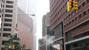 New York Su Sokağı 'nda buhar sızıntısı, turuncu buhar borusu yığını. Pipo dumanı. Con Edisons Buhar Operasyonları Sistemi, Manhattan şehir merkezi finans bölgesi mimarisi. Trafik ışığı