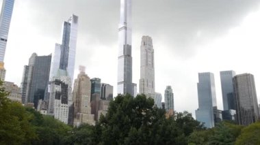 New York Şehri Manhattan Midtown. 5. Cadde 'deki Central Park, ABD. Amerika 'nın simgesi, NYC, ABD' deki şehir parkı. Gökdelen binaları mimarisi, 59 sokak silueti. Yeşil ağaçlar.