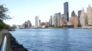 New York şehri kıyısı silueti, Manhattan şehir merkezi binaları, nehir kıyısındaki gökdelenler, doğu nehri suyu. Roosevelt Adası 'ndan deniz kenarı manzarası. Birleşik Devletler mimarisi ve gayrimenkul.