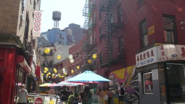 New York, ABD - 14 Eylül 2023: Manhattan Chinatown Doyers Caddesi, Çin etnik bölge mimarisi. İnsanlar, şenlikli kağıt fenerler, sokak yemeği şemsiyeleri. Su kulesi tankı.