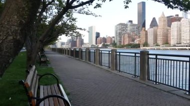 New York şehri kıyısı silueti, Manhattan şehir merkezi binaları, nehir kıyısındaki gökdelenler, doğu nehri suyu. Roosevelt Adası 'ndan deniz kenarı manzarası. Birleşik Devletler mimarisi ve gayrimenkul.