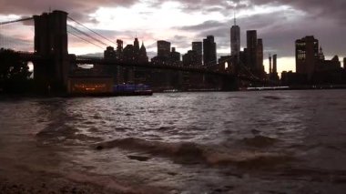 Brooklyn Köprüsü, New York City Manhattan şehir merkezi silueti, finans bölgesi şehir manzarası. Birleşik Devletler Dünya Ticaret Merkezi gökdeleni. Waterfront Pebble Sahili, Dumbo, ABD. Dramatik alacakaranlık bulutlu gökyüzü.