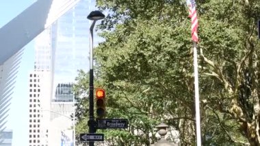Broadway sokak tabelası, Manhattan şehir merkezi finans bölgesi mimarisi, New York, Fulton sokak köşesi. Trafik levhası. Dünya Ticaret Merkezi yakınlarında sarı trafik ışığı. Amerikan bayrağı.