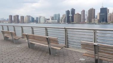 New York şehri kıyısı silueti, Manhattan şehir merkezi binaları, nehir kıyısındaki gökdelenler, doğu nehri suyu. Waterside City, Gantry Plaza Park, Long Island, Queens, ABD. Nehir kenarındaki bank.