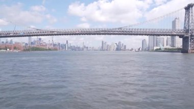 Feribottan New York City silueti. Manhattan şehir merkezindeki gökdelenler feribottan görünüyor. Doğu nehri kıyısı manzarası, nehir kıyısındaki binalar ABD suları yakınında. Williamsburg Köprüsü